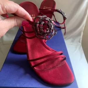 Stuart Weitzman “Ramblin Rose” heels in ruby red satin with matching brooch.